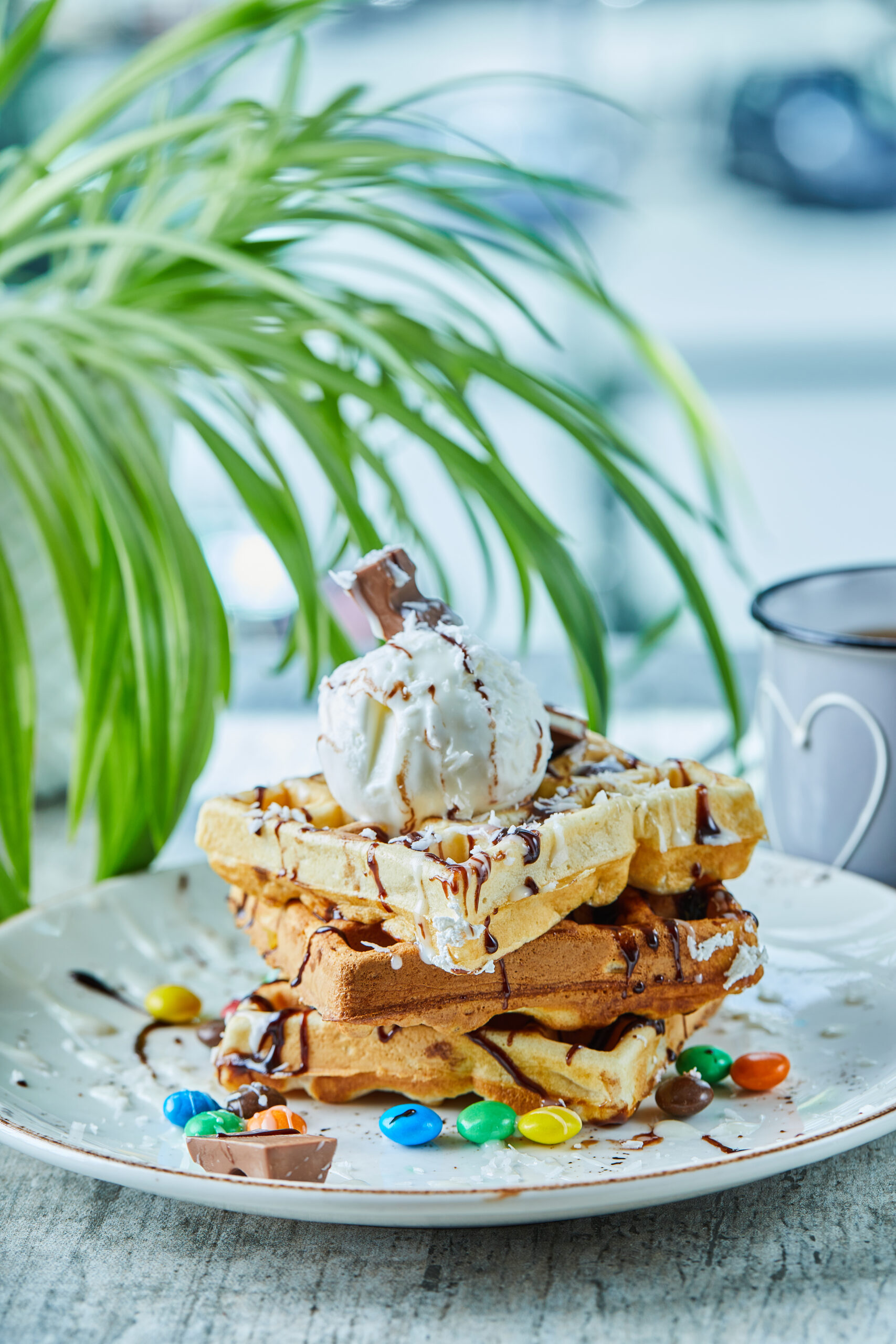 Waffles with ice-cream, chocolate, M$M's on the white plate with tea